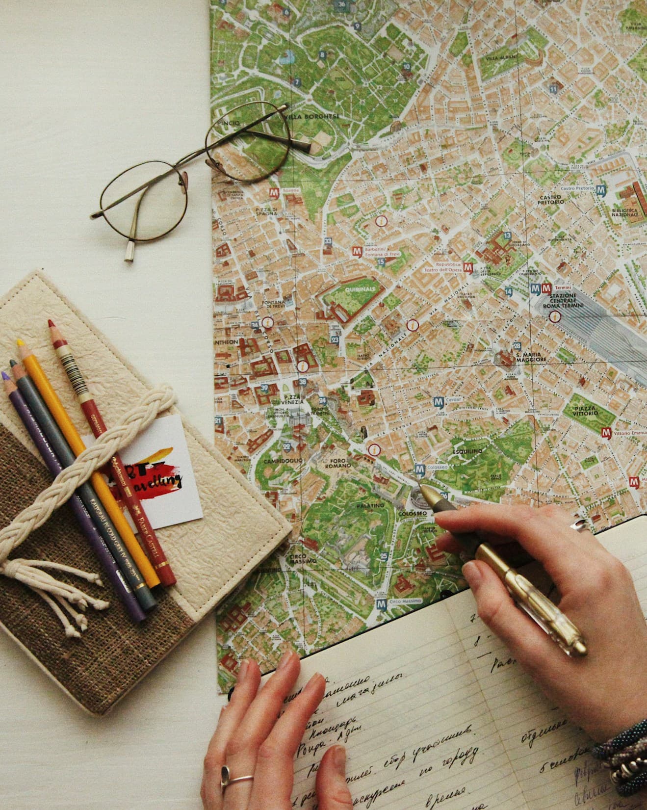 Hand tracing a route on a city map beside coloured pencils