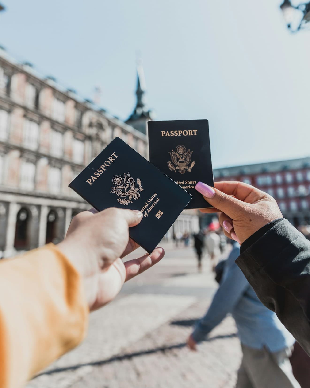 Two travellers holding up their passports in a city square