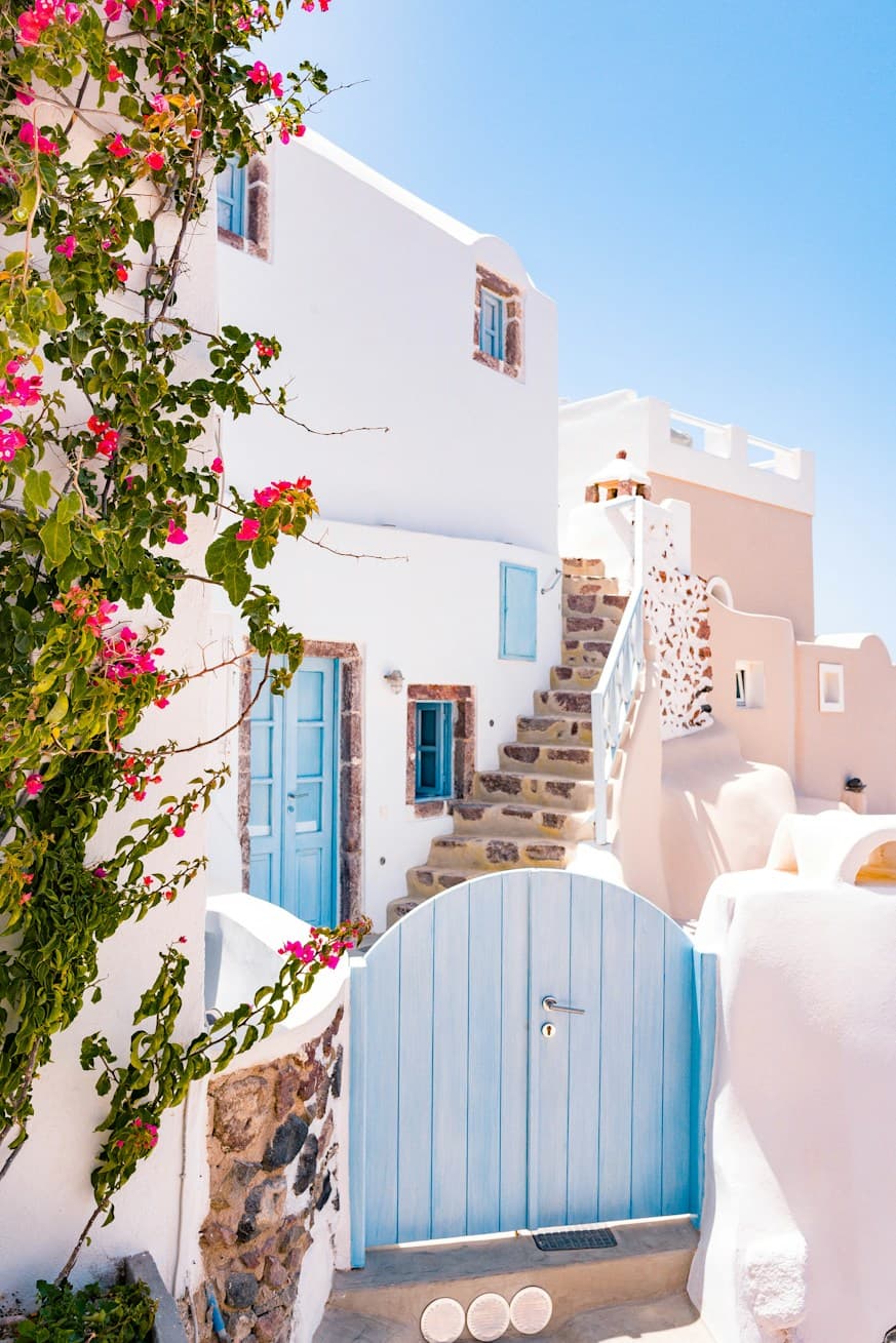Whitewashed Greek island house with a blue gate and bougainvillea